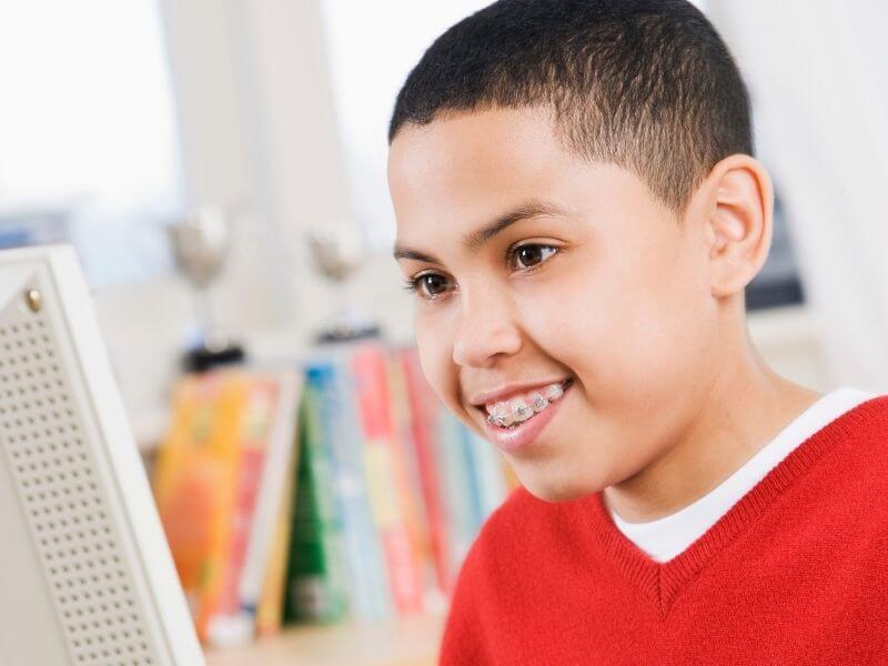 boy doing online homeschooling in front of computer
